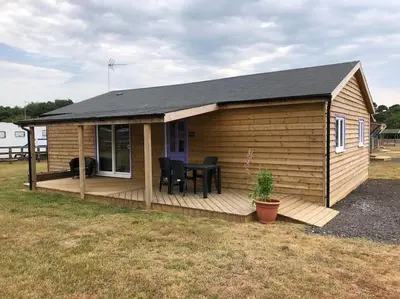 a wooden cabin with a table on a deck at Barn Owl Lodge with Hot Tub - Adults Only in Lackford