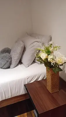 a bed with white pillows and a table with flowers at Number 14 in Ipswich