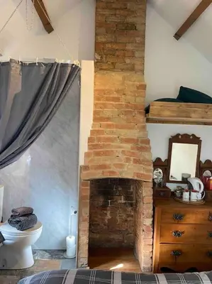 a room with a brick fireplace in a bedroom at The old wash house in Denver