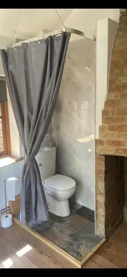 a bathroom with a toilet with a shower curtain at The old wash house in Denver