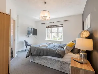 a bedroom with a bed and a table with a lamp at Comfortable home Langdon Hills - Pass the Keys in Basildon