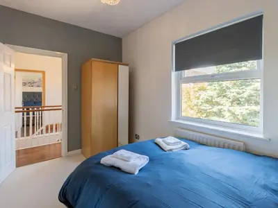 a bedroom with a blue bed and a window at Comfortable home Langdon Hills - Pass the Keys in Basildon
