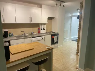 a kitchen with white cabinets and a wooden counter top at Right by Leigh Broadway Private Garden large ground fl apt in Southend-on-Sea