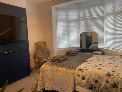 a bedroom with a bed and a large window at Right by Leigh Broadway Private Garden large ground fl apt in Southend-on-Sea