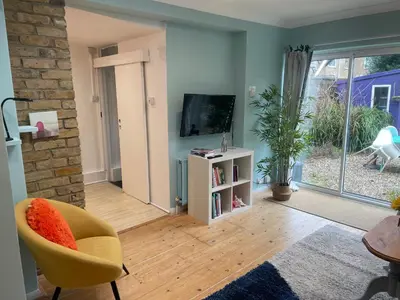 a living room with a tv and a yellow chair at Right by Leigh Broadway Private Garden large ground fl apt in Southend-on-Sea