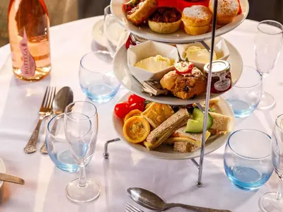 a table topped with plates of food and glasses of wine at The Harlow Hotel By AccorHotels in Harlow