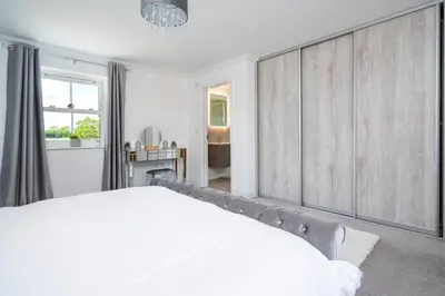 a white bedroom with a large bed and a window at Kestral House in Eye