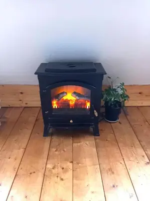 a black stove sitting on top of a wooden floor at Rustic Retreat Guest Lodge in Littleport