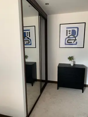 a mirror in a room with a black dresser and a table at The Sunrise Den-Lovely 2 bedroom apartmentParking in Harlow