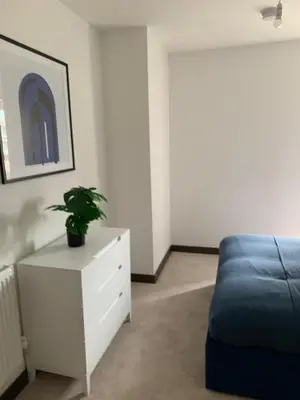 a bedroom with a blue couch and a white dresser at The Sunrise Den-Lovely 2 bedroom apartmentParking in Harlow