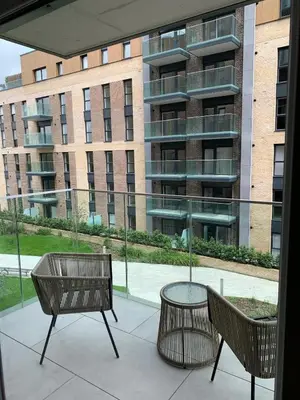 a patio with two chairs and a table and a building at The Sunrise Den-Lovely 2 bedroom apartmentParking in Harlow