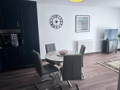 a dining room with a table and chairs and a clock at The Sunrise Den-Lovely 2 bedroom apartmentParking in Harlow