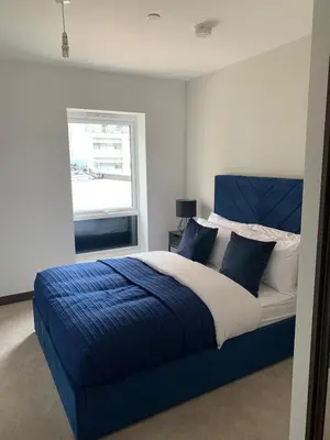 a bedroom with a blue and white bed with a window at The Sunrise Den-Lovely 2 bedroom apartmentParking in Harlow