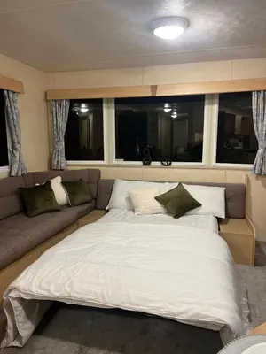 a large bed in a room with a couch at 3 Bedroom Caravan - Sleeps 8 - Parking Wifi Pool in Clacton-on-Sea