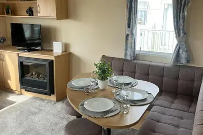 a living room with a table and a couch at 3 Bedroom Caravan - Sleeps 8 - Parking Wifi Pool in Clacton-on-Sea
