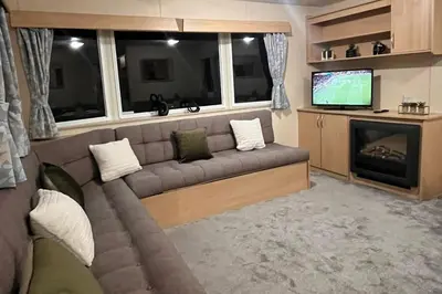 a living room with a couch and a television at 3 Bedroom Caravan - Sleeps 8 - Parking Wifi Pool in Clacton-on-Sea