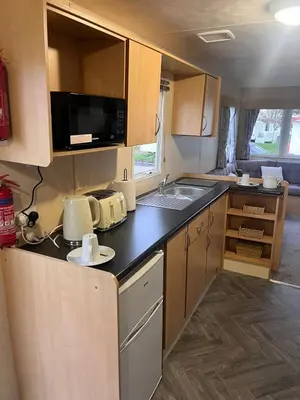 an rv kitchen with a sink and a microwave at 3 Bedroom Caravan - Sleeps 8 - Parking Wifi Pool in Clacton-on-Sea