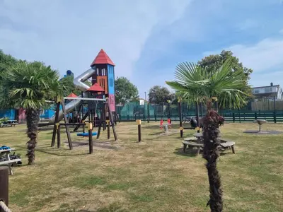 a playground with a slide in a park with palm trees at 3 Bedroom Caravan - Sleeps 8 - Parking Wifi Pool in Clacton-on-Sea