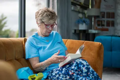 a woman sitting on a couch reading a book at Glass House Retreat in Puddle Dock
