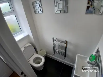 a bathroom with a toilet and a window and a sink at Hornchurch House - Jackson Close in Harold Wood