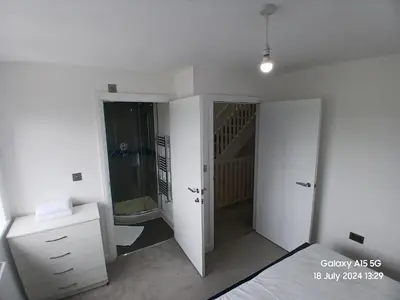 a white bedroom with a bed and a bathroom at Hornchurch House - Jackson Close in Harold Wood
