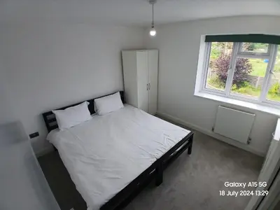 a bedroom with a bed with white sheets and a window at Hornchurch House - Jackson Close in Harold Wood