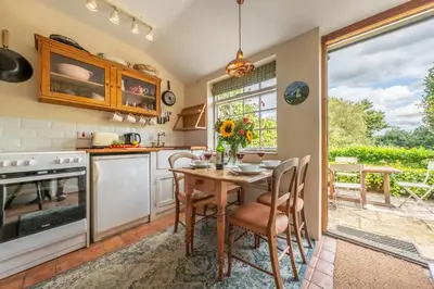 a kitchen with a table and chairs and a window at Brimming with Medieval charm - Weavers Cottage in Lavenham