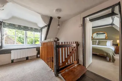 a bedroom with a bed and a large window at Brimming with Medieval charm - Weavers Cottage in Lavenham