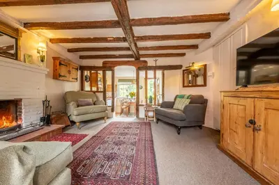 a living room with chairs and a fireplace at Brimming with Medieval charm - Weavers Cottage in Lavenham