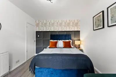 a bedroom with a bed with blue and orange pillows at Spacious 4 Bed In Cambridge - Garden - Games Room in Cherry Hinton