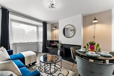 a living room with a blue couch and a table at Spacious 4 Bed In Cambridge - Garden - Games Room in Cherry Hinton