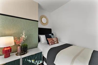 a bedroom with a bed and a table with a lamp at Spacious 4 Bed In Cambridge - Garden - Games Room in Cherry Hinton