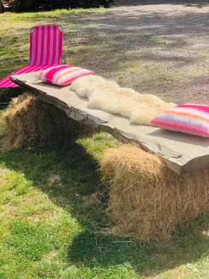 a chair sitting on a pile of hay with pillows at HERTFORD Farm yurt Tent Camping fire pit bbq pet friendly in Hertford