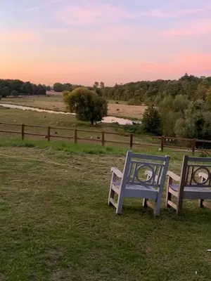 two blue benches sitting in a field near a fence at HERTFORD Farm yurt Tent Camping fire pit bbq pet friendly in Hertford