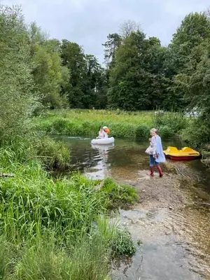 two children standing in a river with a boat at HERTFORD Farm yurt Tent Camping fire pit bbq pet friendly in Hertford