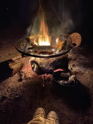 a person is standing in front of a fire at HERTFORD Farm yurt Tent Camping fire pit bbq pet friendly in Hertford
