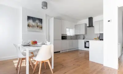 a white kitchen with a white table and chairs at Stunning Spacious 4 Bed bungalow in Southend-on-Sea