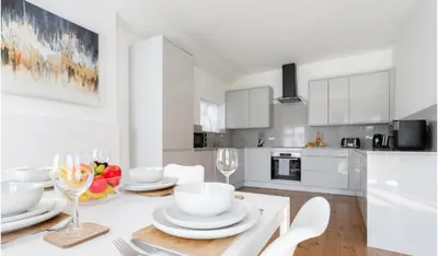 a white kitchen with a table with plates and wine glasses at Stunning Spacious 4 Bed bungalow in Southend-on-Sea