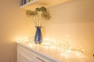 a blue vase sitting on a mantle with lights at Olive Cottage, Wickham Market in Wickham Market