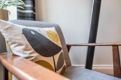 a pillow on a chair with a bird on it at Olive Cottage, Wickham Market in Wickham Market