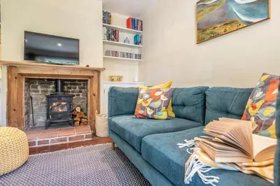 a living room with a blue couch and a fireplace at Olive Cottage, Wickham Market in Wickham Market