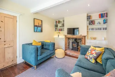 a living room with two blue chairs and a fireplace at Olive Cottage, Wickham Market in Wickham Market