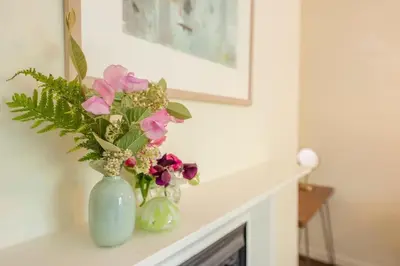 two vases with flowers sitting on a fireplace mantle at Olive Cottage, Wickham Market in Wickham Market
