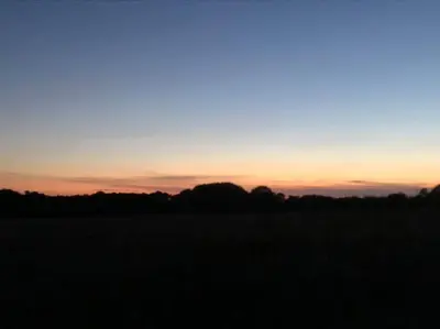 a silhouette of a field with a sunset in the background at Wagtail Lodge in Lackford