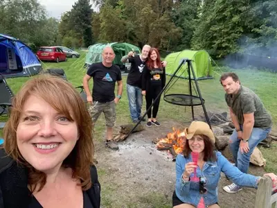 a group of people standing around a campfire at Goldings Farm yurt Tent firepit bbq activities in Bramfield