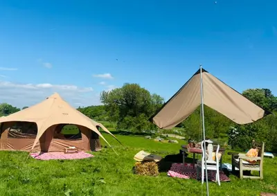 a couple of tents in a field with chairs at Goldings Farm yurt Tent firepit bbq activities in Bramfield