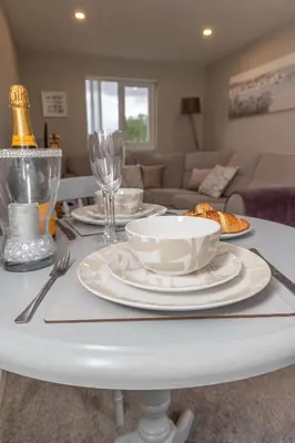 a white table with plates and wine glasses on it at The Retreat- amazing scenic views of the Essex countryside! in Salcott