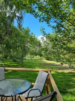 a table and chairs on a porch with a view of a park at The Duck - Free Fishing, pets welcome - static caravan in Clare, Suffolk in Sudbury