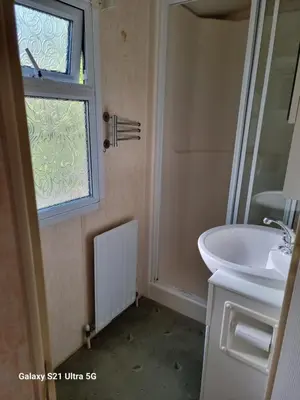 a bathroom with a sink and a window at The Duck - Free Fishing, pets welcome - static caravan in Clare, Suffolk in Sudbury