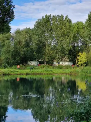 a view of a lake with houses in the background at The Duck - Free Fishing, pets welcome - static caravan in Clare, Suffolk in Sudbury